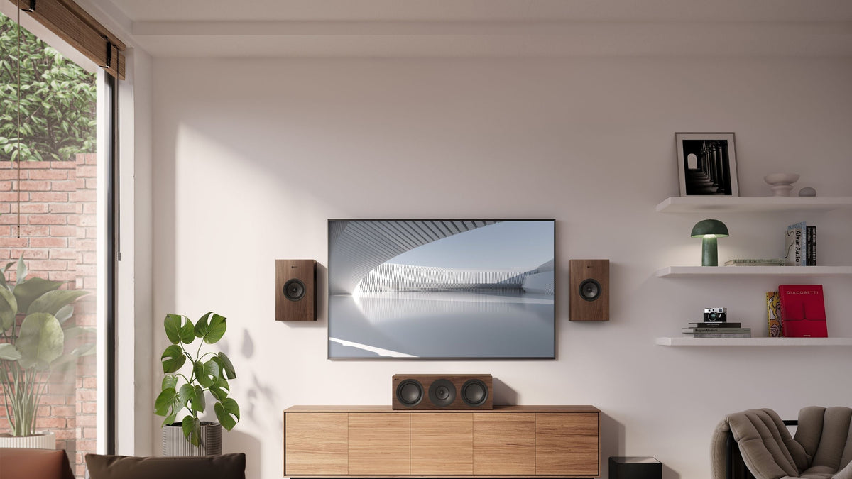A stylish living room showcasing a KEF Q series HiFi speaker setup with Q4 Meta & Q6 Meta, couch, a television, and a large window that provides ample daylight. 