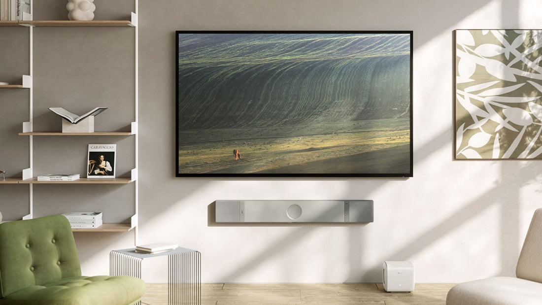 Modern living room with wall-mounted TV and sleek KEF soundbar, illustrating premium home cinema setup in natural light.