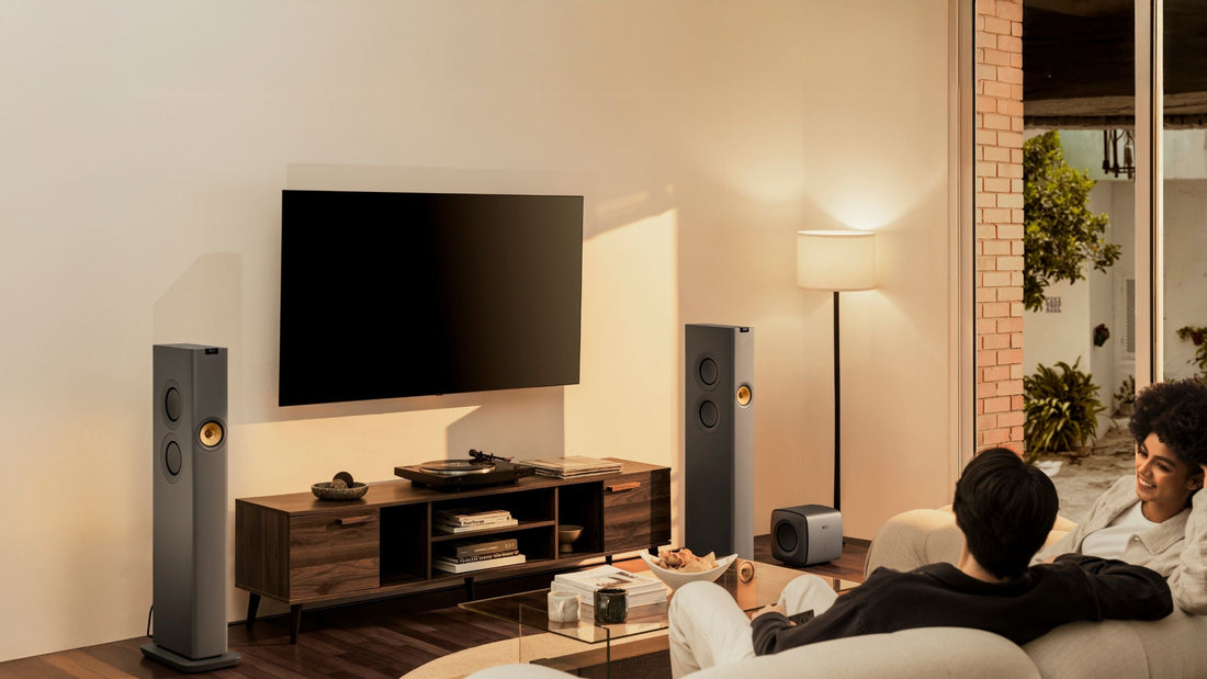 KEF LS60 Wireless speaker placed living in a room whilst couple sitting on a sofa