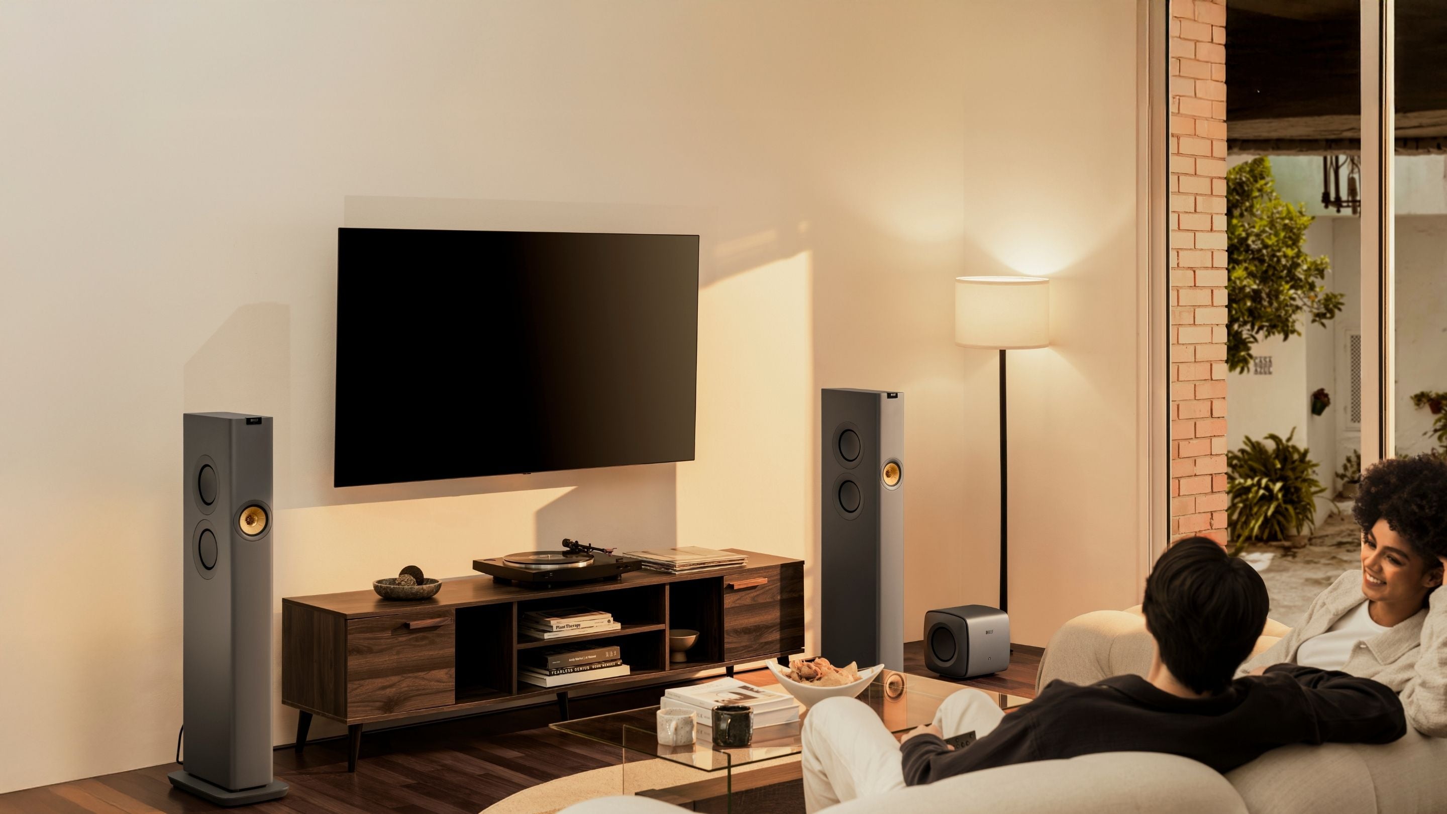 KEF LS60 Wireless speaker placed living in a room whilst couple sitting on a sofa