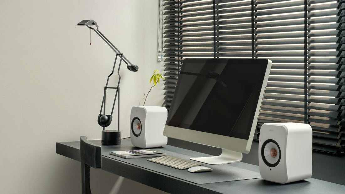 KEF LSX II Speakers placed on modern desk between a monitor