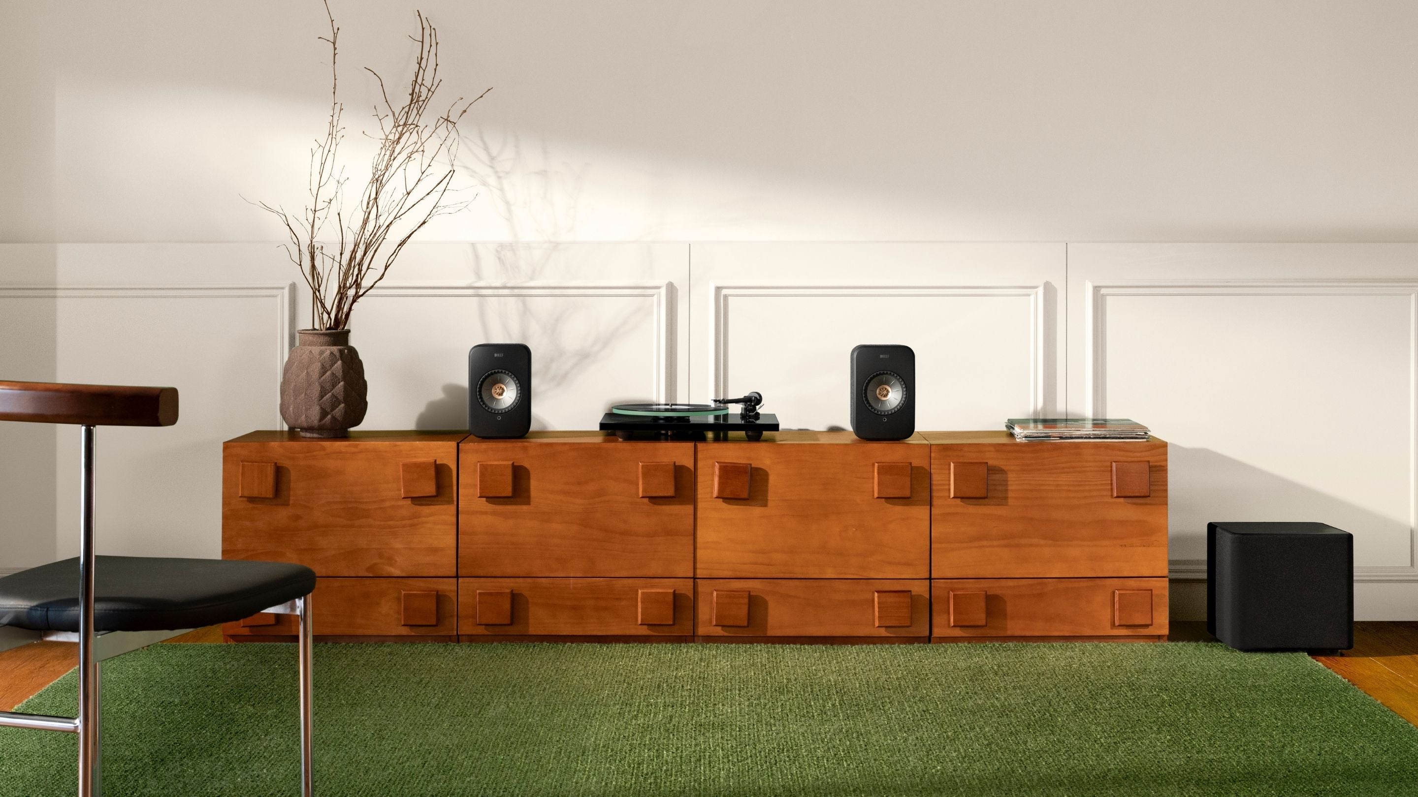 Wooden entertainment console with speakers and decor in a room with green carpet.