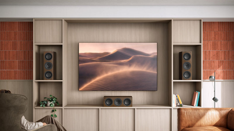 Three KEF R6 Meta Centre channel speakers LRC placed next to a mounted TV while one speaker is placed below the TV